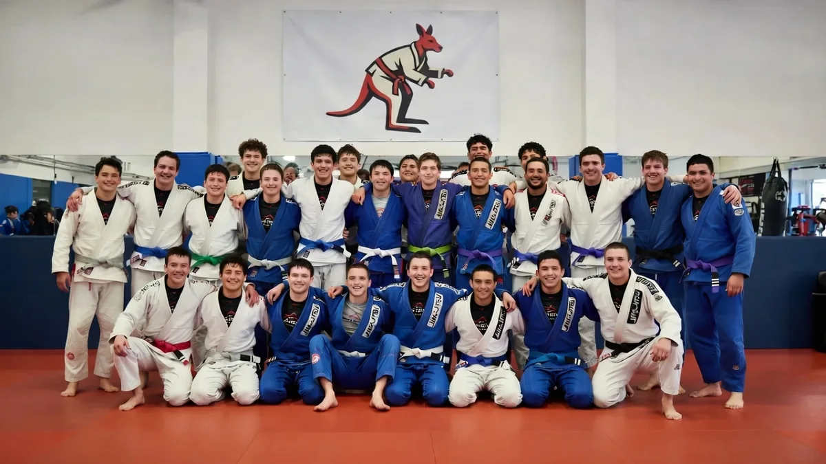 About twenty Outback BJJ Online members in gis posed together for a team photo under the kangaroo logo banner inside the gym